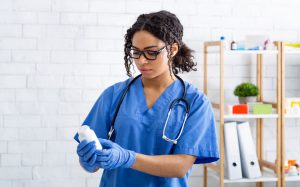 Young female veterinary doctor holding bottle of prescription pills at animal hospital Vet choosing medication